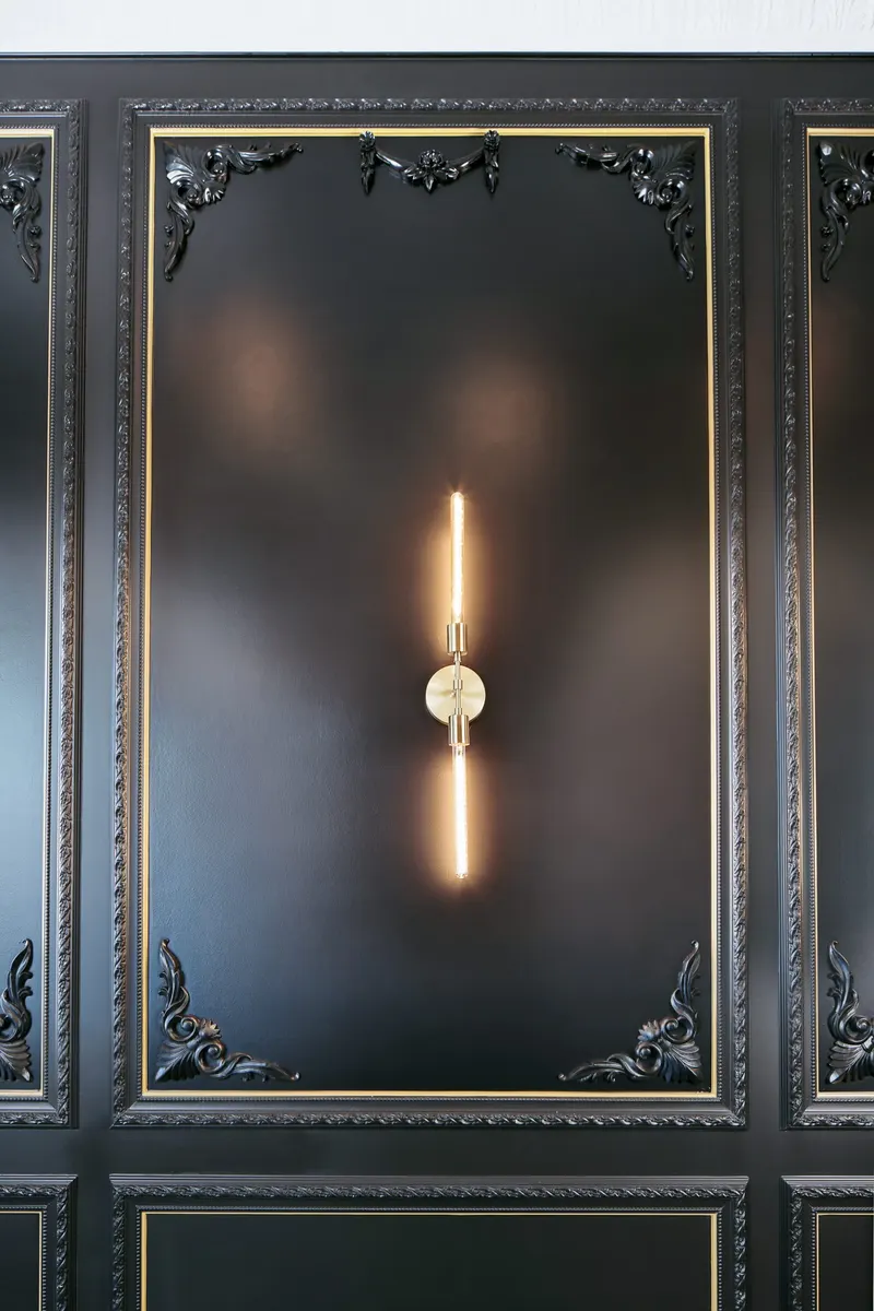 Black molded wall panel with brass sconce
