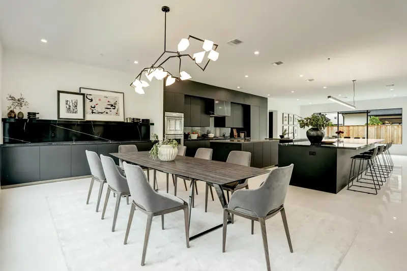 Dining room and kitchen with a sculptural chandelier and black island