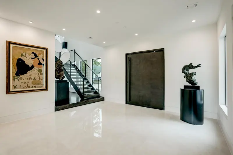 Foyer with an oversized pivot door and floating glass staircase