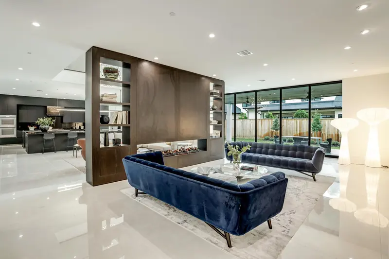 Living room with a floating walnut shelving divider and floor-to-ceiling glass