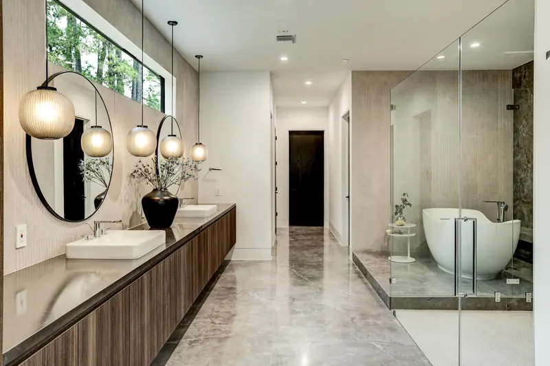 Primary bath with round mirrors, globe pendants, walk-in glass shower and freestanding tub