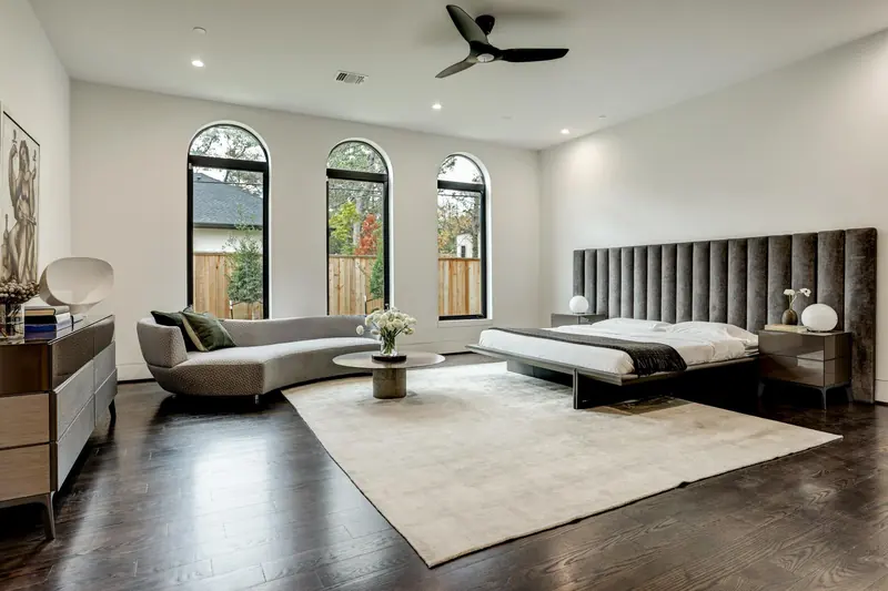 Primary bedroom with arched windows and a channel-tufted headboard wall