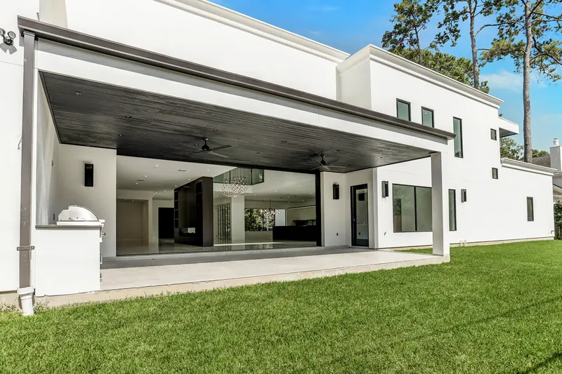 Rear exterior with a deep covered patio and open lawn