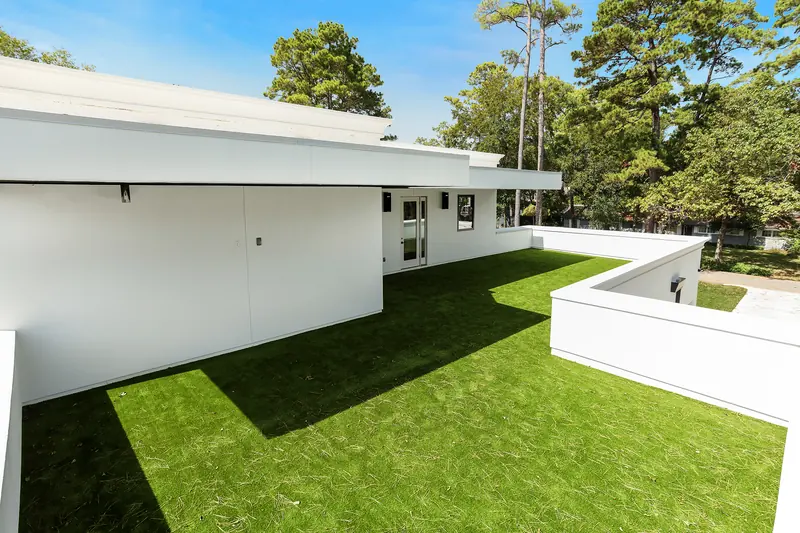 Private rooftop lawn terrace framed by white parapet walls