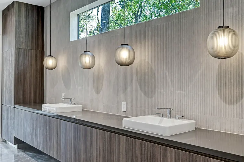 Walnut vanity with vessel sinks under a ribbon of clerestory windows