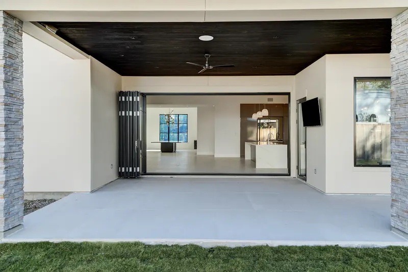 Covered patio with stone columns and folding glass doors to the living room
