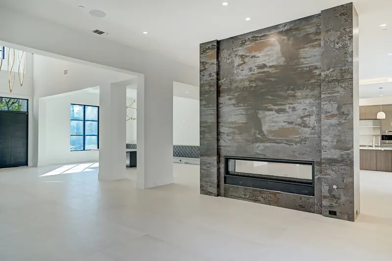 Freestanding stone double-sided fireplace between living spaces