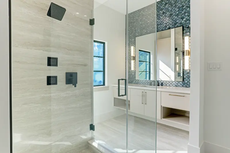 Frameless glass shower with stone walls and mosaic accent niche