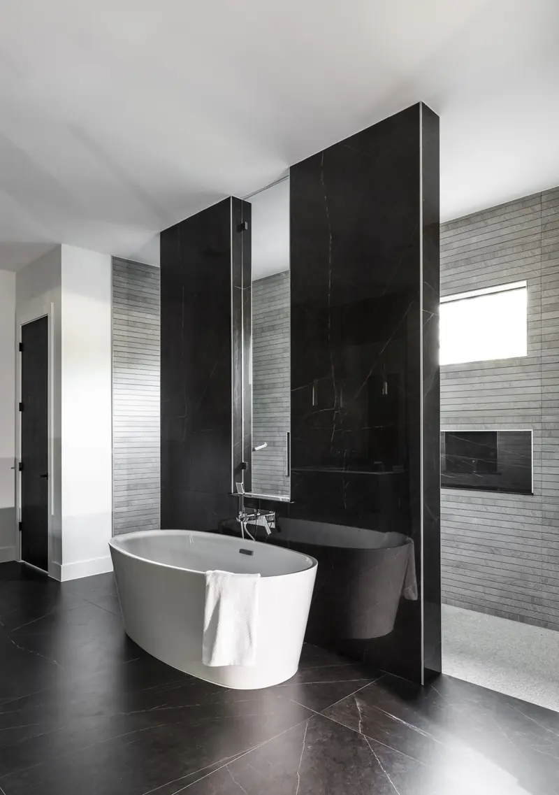 Freestanding tub framed by black stone panels