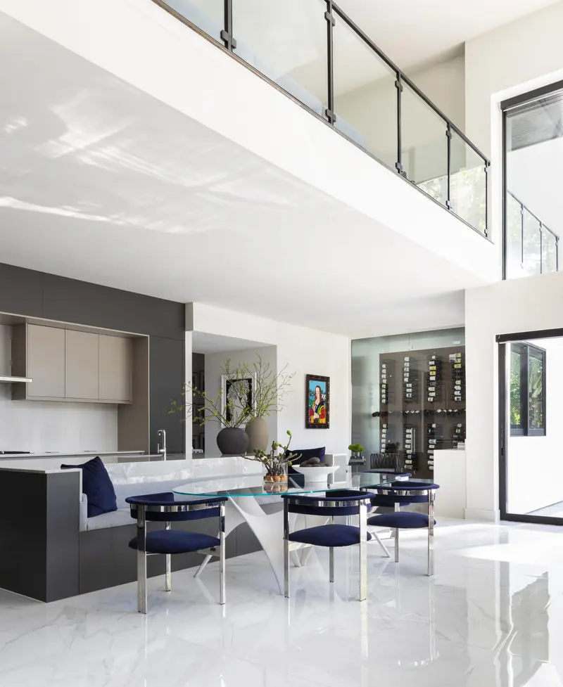 Kitchen and dining area beneath a glass-railed catwalk