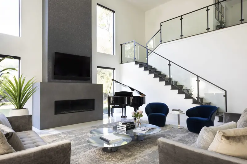 Double-height living room with a fireplace tower, grand piano and floating stair