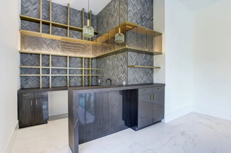 Bar with herringbone tile backsplash and brass-framed open shelving