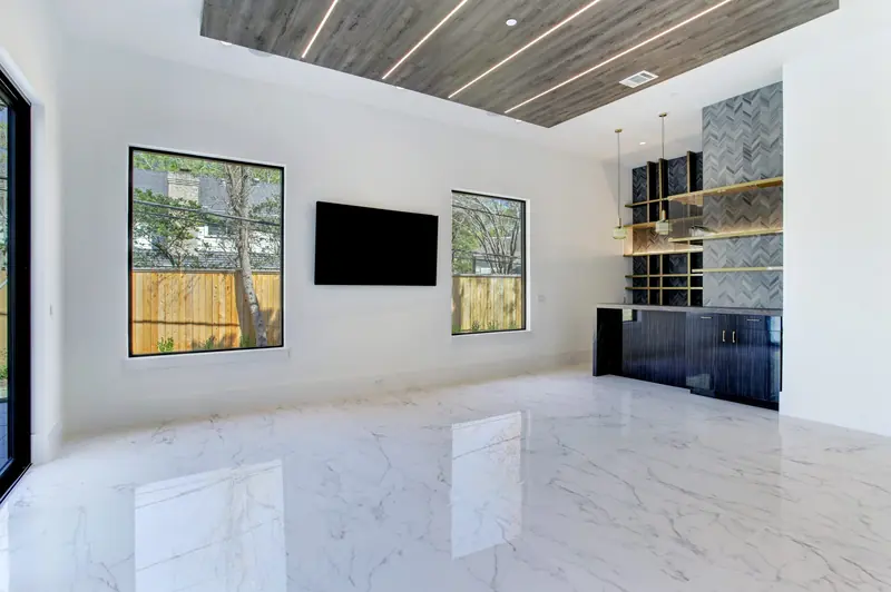 Game room with a wood-slat ceiling, media wall and wet bar