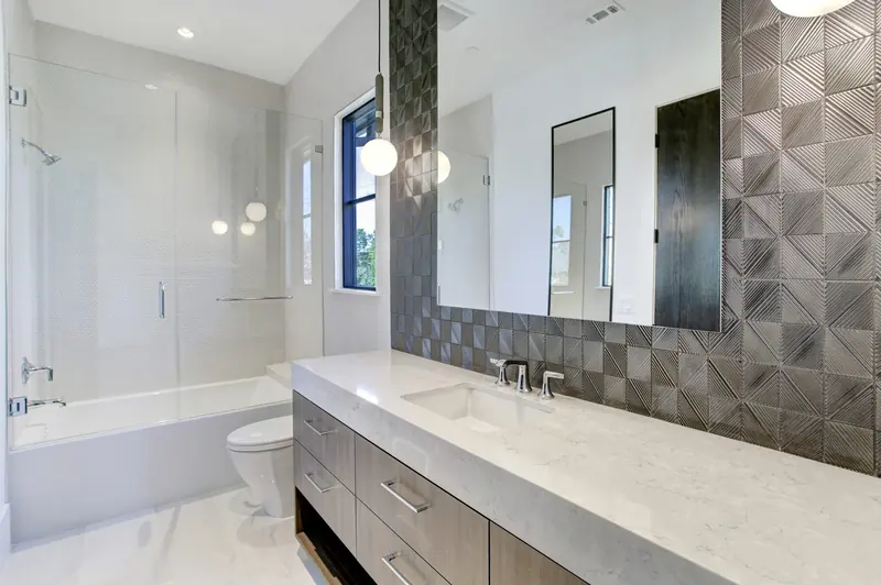 Guest bath with sculptural gray tile and a floating quartz vanity