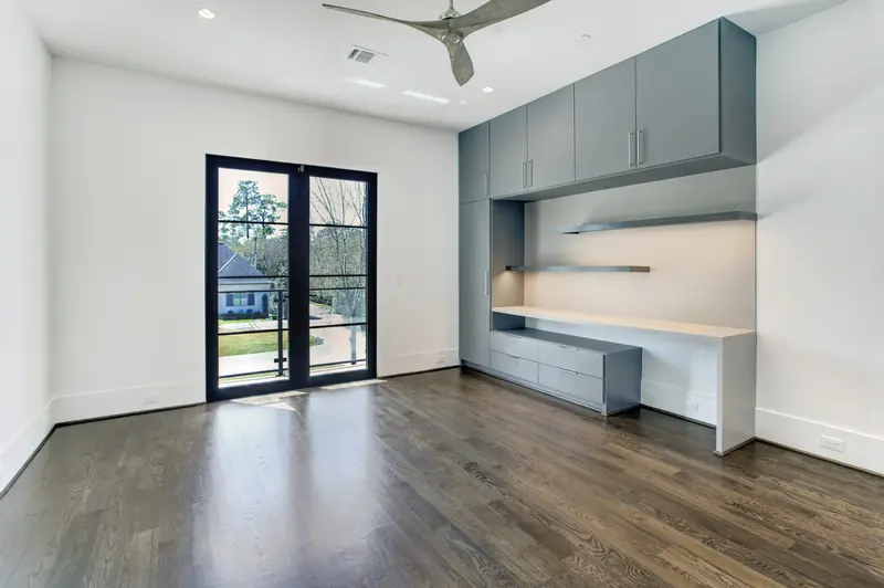 Home office with built-in desk, cabinetry and French doors