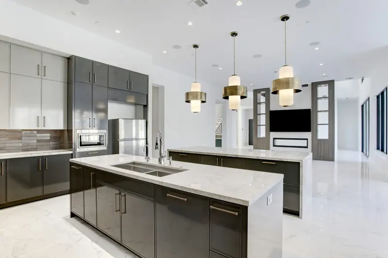 Kitchen with two islands, brass pendant lights and a built-in refrigerator wall