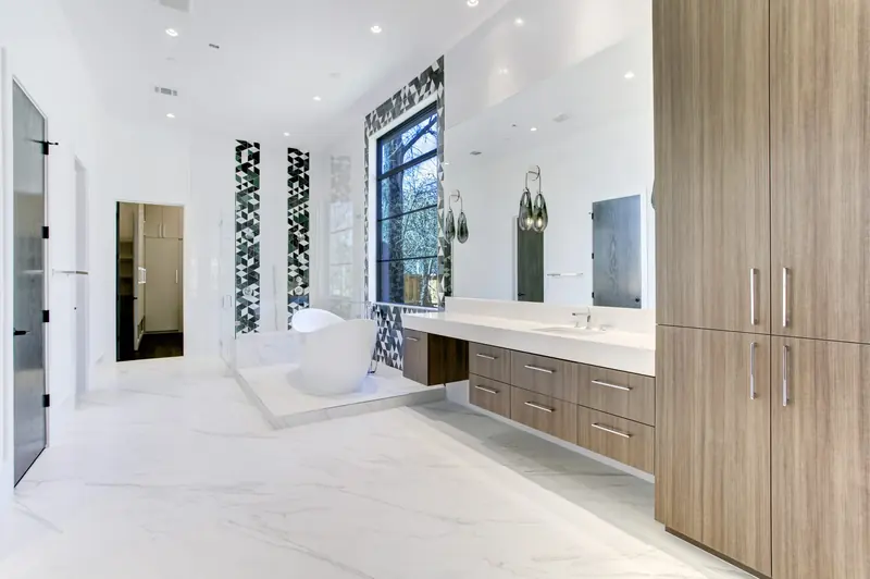Primary bath with a freestanding tub, floor-to-ceiling window and wood vanity