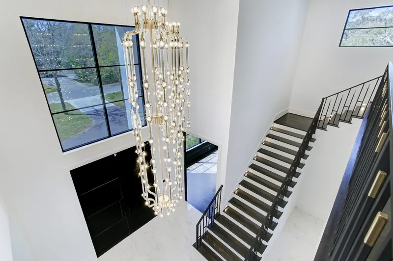 Floating staircase with a two-story crystal chandelier and window wall