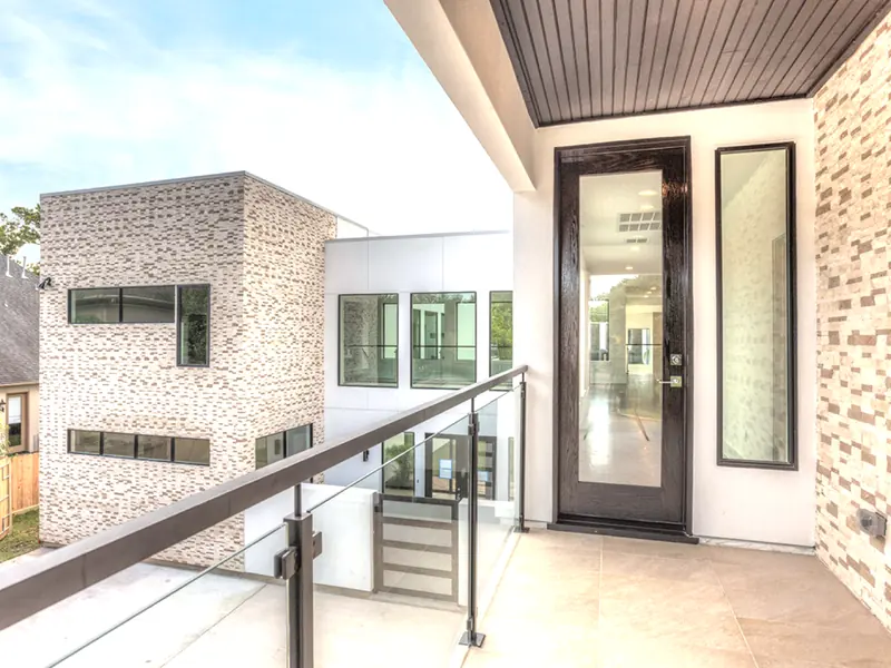 Upper balcony with glass railing and a pivot entry door