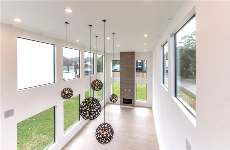 Double-height living room with sculptural pendant lights and a stone fireplace column
