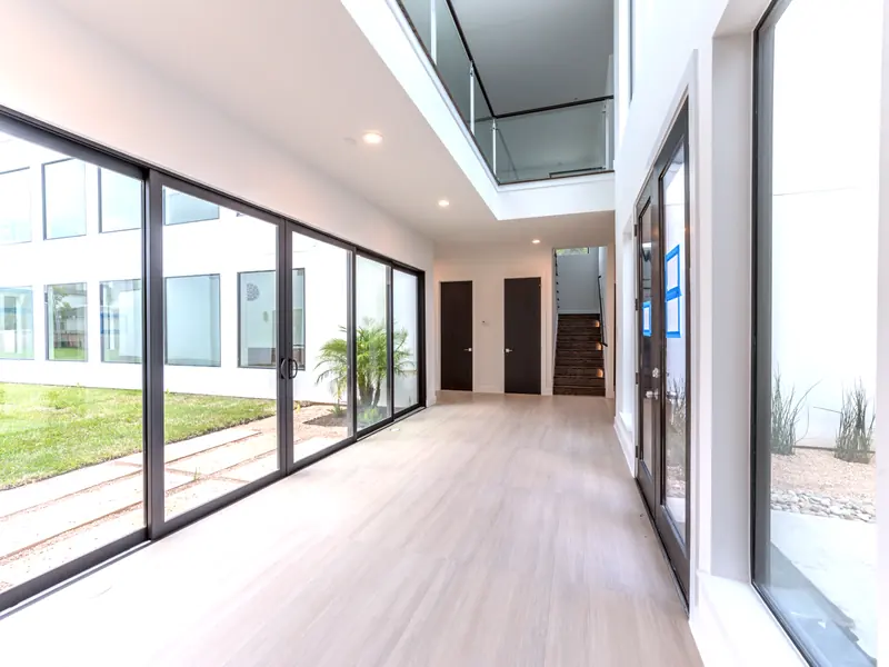 Gallery hallway lined with floor-to-ceiling sliding glass to the courtyard