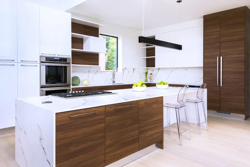Kitchen with walnut cabinetry, marble counters and linear pendant