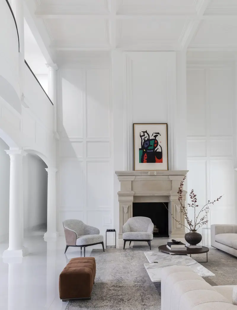 Two-story sitting room with a carved limestone fireplace and paneled walls