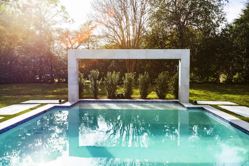 Pool with a sculptural stone-frame fountain at sunset