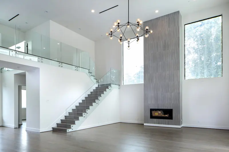 Double-height living room with fireplace column, floating stair and glass railings