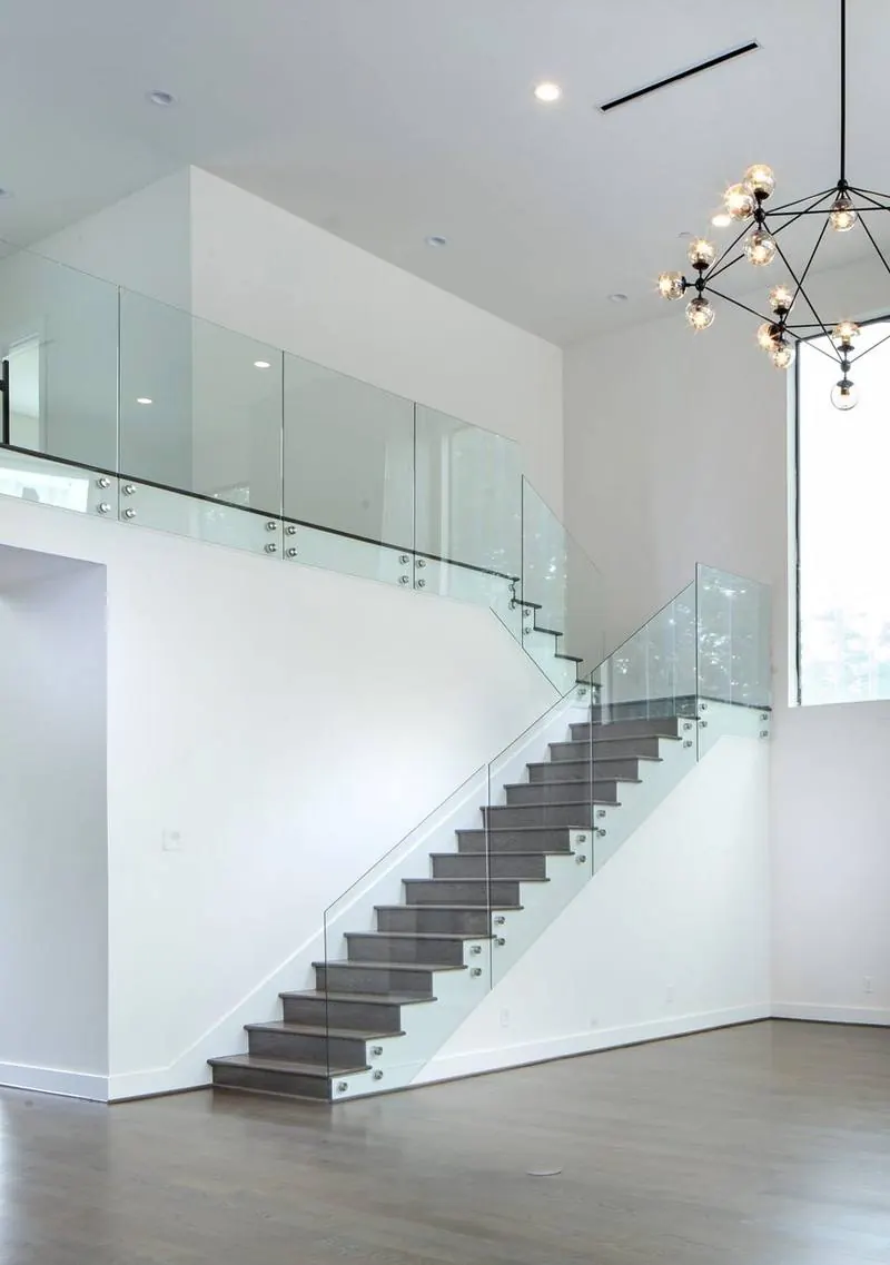 Floating stair with glass rail and sculptural chandelier in a Capital Builders great room