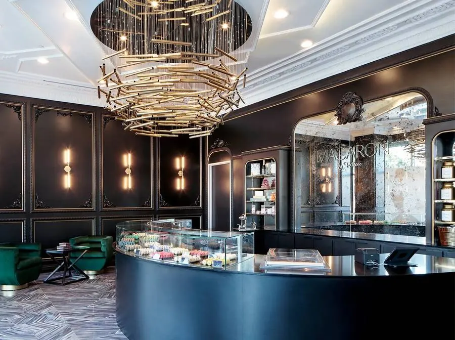 Macaron By Patisse bakery with a sculptural gold chandelier over a curved display counter